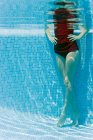Mulher de pé com as mãos nos quadris na piscina, vista subaquática — Fotografia de Stock