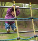 Jeune fille sur le cadre d'escalade dans l'aire de jeux, portrait — Photo de stock