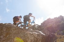 Jovem casal em bicicletas de montanha em rochas — Fotografia de Stock