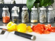 Cooking ingredients on cutting board and herbs in jars — Stock Photo