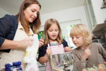 Mid adult woman baking with son and daughter in kitchen — Stock Photo