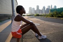 African american runner sitting on sidewalk — Stock Photo