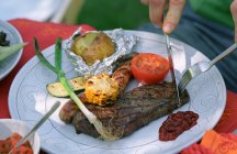 Abgeschnittenes Bild eines Mannes, der Steak auf Teller schneidet — Stockfoto