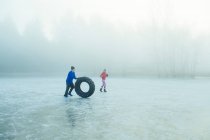 Man rolling tyre on frozen lake — Stock Photo