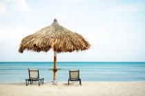Parasol et chaises longues sur la plage — Photo de stock