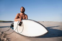 Серфер на пляжі з серфбордом — стокове фото