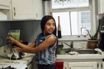 Girl preparing smoothie in blender in kitchen — Stock Photo
