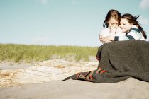 Mädchen umarmen sich in Decke am Strand — Stockfoto