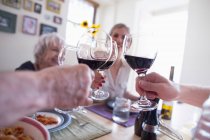 Brindisi in famiglia con vino rosso a tavola — Foto stock