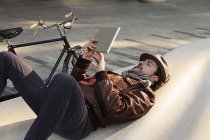 Mittlerer erwachsener Mann auf dem Rücken liegend mit digitalem Tablet — Stockfoto
