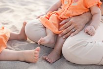 Мати сидить з дочками на пляжі, низька секція — стокове фото