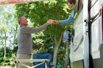 Mujer ofreciendo hombre taza fuera campervan - foto de stock