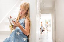 Девушка в коридоре с цифровым планшетом — стоковое фото