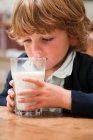 Молодий хлопчик п'є велику склянку молока — стокове фото
