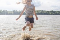 Chica saltando y salpicando en el río - foto de stock