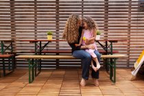 Mother and daughter sitting on bench on patio — Stock Photo