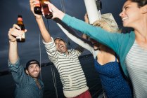 Freunde stoßen mit Bierflaschen auf Segelboot an — Stockfoto
