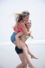 Jeune femme sur piggyback sur la plage — Photo de stock
