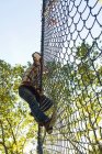 Homme adulte moyen grimpant sur une clôture à maillons de chaîne — Photo de stock
