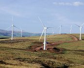 Turbinas eólicas em colinas verdes com céu azul nublado — Fotografia de Stock