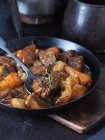 Beef with onion, carrots, rosemary and potatoes in vintage pan — Stock Photo