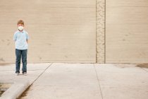 Young boy standing by brick wall wearing dust mask — Stock Photo