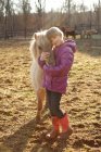 Portrait of young girl outdoors, hugging pony — Stock Photo