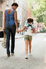 Mother and daughter walking along street, rear view — Stock Photo