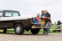 Family with produce in truck bed — Stock Photo