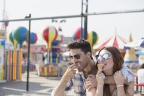 Couple contemporain passer un bon moment sur le parc d'attractions promenade manger de la crème glacée molle — Photo de stock