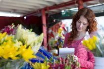 Florist macht sich Notizen im Geschäft — Stockfoto
