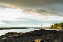 Distant view of senior man looking through binoculars at coast of Maine, USA — Stock Photo