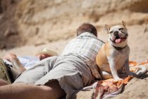 Männer entspannen sich mit Hund am Strand — Stockfoto