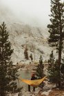 Вид сзади на мужчину-туриста, сидящего в гамаке у озера, Mineral King, Национальный парк Секвойя, Калифорния, США — стоковое фото