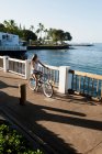 Woman riding bicycle on waterfront — Stock Photo