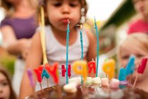 3 year old girl blowing out candles on birthday cake — Stock Photo