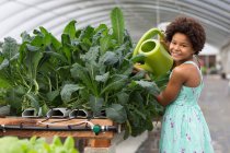 Mädchen gießt Pflanzen im Gewächshaus — Stockfoto