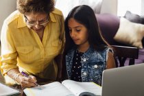 Бабуся допомагає онуці з домашнім завданням — стокове фото