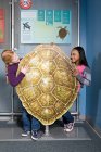 Deux filles debout derrière coquille de tortue de mer verte — Photo de stock