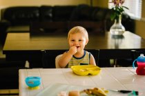 Молодий хлопчик їсть їжу за столом — стокове фото