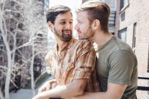 Männliches Paar steht auf Balkon, umarmt sich, Gesicht an Gesicht — Stockfoto