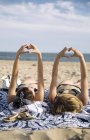 Women lying on beach blanket, showing heart-shaped gesture, Amagansett, New York, USA — Stock Photo