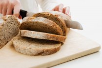 Imagen recortada de panadero rebanando pan aislado en blanco - foto de stock