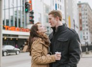 Young couple standing in street, face to face, sticking out tongues — Stock Photo