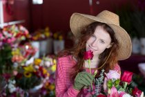 Florista cheirar flores na loja — Fotografia de Stock
