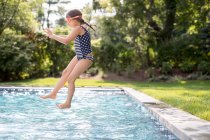 Fille sauter dans la piscine extérieure — Photo de stock