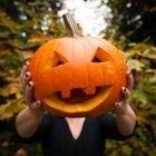 Mujer sosteniendo calabaza tallada - foto de stock