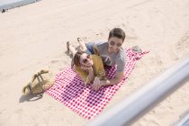 Contemporary couple having a good time rleaxing on the beach on blanket — Stock Photo