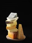 Cheese selection stacked on cheese board with black background — Stock Photo