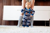 Мать помогает маленькому сыну сделать первые шаги — стоковое фото
